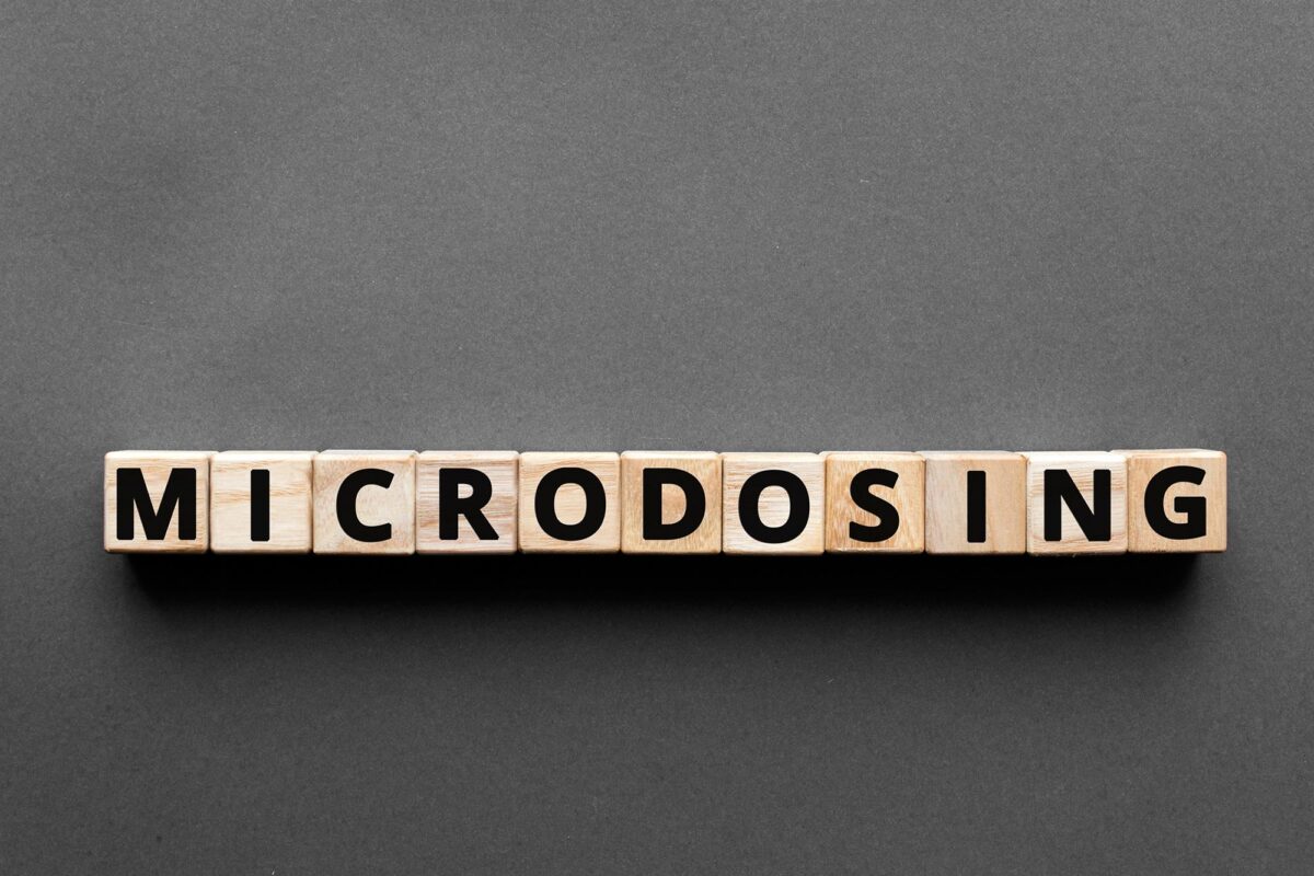 Wooden letter blocks spelling out the word microdosing on a grey background, representing a 30-day psilocybin microdosing experiment and its effects on mood, creativity and mental health